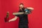 One young caucasian man with cactus and electric saw posing over red background.