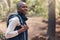 One young handsome african american male backpacker hiking outdoors in the woods. Confident and happy black man walking