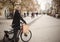 One young man, 20-29 years, standing in, pedestrian only, street holding his bicycle, and smiling to camera, with shopping bag.