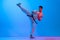 One young man, karate fighter in white kimono in action, motion isolated on blue background in neon. Sport, action