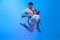 One young man, karate fighter in white kimono in action, motion isolated on blue background in neon. Sport, action