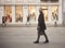 One young smiling and happy man, 20-29 years old, handsome and stylish, walking in city street with no cars, pedestrians walking