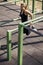 One young woman, 20-29 years, exercising outdoors in public park, outdoor gym, doing pull ups, push up,