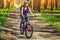 One young woman - an athlete in a helmet riding a mountain bike outside the city, on the road in a pine forest