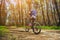 One young woman - an athlete in a helmet riding a mountain bike outside the city, on the road in a pine forest