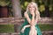 One young woman portrait, sitting in wood bench, green dress, 25 years old, smiling happy, looking to camera.