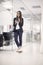 One young woman, white collar worker, standing enjoying her work, using tablet. full lenght shot, in modern interior office space