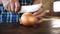 Onion cutting by knife on chop block.