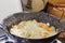 Onion rings, carrot slices and several spice herbs are being cooked in a casserole