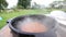 Onions and carrots are fried in a cast-iron cauldron. Visible smoke and steam. Cooking outdoors