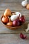 Onions and dried husk in a clay bowl on wooden boards