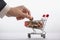Online commerce and banking concept, businessman`s hand stacks coins in supermarket trolley, cashback background