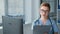 online doctor in glasses writes in clipboard in front of computer monitor, young woman wearing blue uniform with