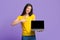 Online Education. Cheerful Korean Girl Holding Laptop And Pointing At Black Screen