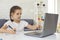 Online education. Video lesson school for children. A little girl is watching a video lesson in a laptop sitting at a