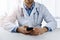 Online medical consultation - physician sitting by the table and using smart phone