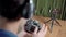 Online photography course. A young man is sitting at a table in headphones watching a video lesson on a smartphone on