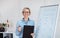 Online schooling. Positive German teacher posing near blackboard with grammar rules, looking at camera and smiling