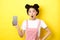 Online shopping concept. Excited stylish asian girl say wow, showing empty cell phone screen and look amazed, yellow