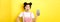 Online shopping concept. Excited stylish asian girl say wow, showing empty cell phone screen and look amazed, yellow