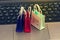 Online shopping concept, Three colorful paper shopping bags on notebook keyboard. E-commerce is the purchase of products and servi