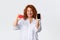 Online shopping, internet banking and money transfer concept. Cheerful smiling adult redhead woman showing smartphone