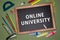 Online university written on chalkboard, stationery on green background.