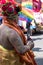 Onlooker looks on at the Gay Pride Parade. Man wears ornate hat, body paint and is partially clothed.