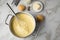 Ooking pot with mashed potatoes and ingredients as potato, milk, salt, butter, nutmeg with whisker and grinder on light marble