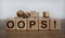 Oops sign on wooden cubes. Wooden table. Beautiful white background, copy space. Concept