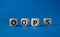 Oops symbol. Concept word Oops on wooden cubes. Beautiful blue background. Business and Oops concept. Copy space