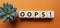 Oops symbol. Concept word Oops on wooden cubes. Beautiful orange background with succulent plant. Business and Oops concept. Copy