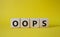 Oops symbol. Concept word Oops on wooden cubes. Beautiful yellow background. Business and Oops concept. Copy space