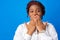 Oops! Young afro woman close mouth with hands against blue background