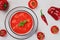 Op view of bowl of gazpacho and fresh tomatoes with sweet peppers on light background