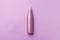 Opaque purple spray cosmetic bottle lying purple background