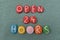 Open 24 Hours, commercial slogan or sign composed with handmade multi colored stone letters over green sand