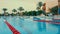 Open air hotel lido with sunbeds and umbrellas in palm trees background.