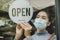 Open. asian small business owner woman wearing protection face mask turning open sign board on glass door for reopening cafe resta