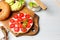 Open bagel sandwich with cream cheese, sweet tomatoes and avocado. Close-up on a light gray background