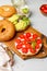 Open bagel sandwich with cream cheese, sweet tomatoes and avocado. Close-up on a light gray background, vertical