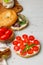 Open bagel sandwich with sweet tomatoes and cream cheese. On a gray light wooden background, a vertical frame.