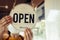 Open. barista, waitress woman wearing protection face mask turning open sign board on glass door in modern cafe coffee shop, cafe