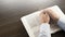 Open Bible book on the table. Prayer. White cup. Young man in shirt prays with folded hands.