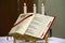 An open Bible and three candles behind it