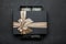 An open black gift box with a golden ribbon and a large bow with money inside. Granite background