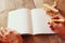 Open blank notebook and woman hands next to toy aeroplane on wooden table. retro style filtered image