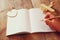 Open blank notebook and woman hands next to toy aeroplane on wooden table. retro style filtered image