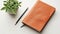 An open blank orange leather diary and a pencil lie on a white desk, ready to capture your thoughts, ideas, and appointments