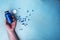 open blue bottle with vitamin pills in the hands of a young man on a blue background